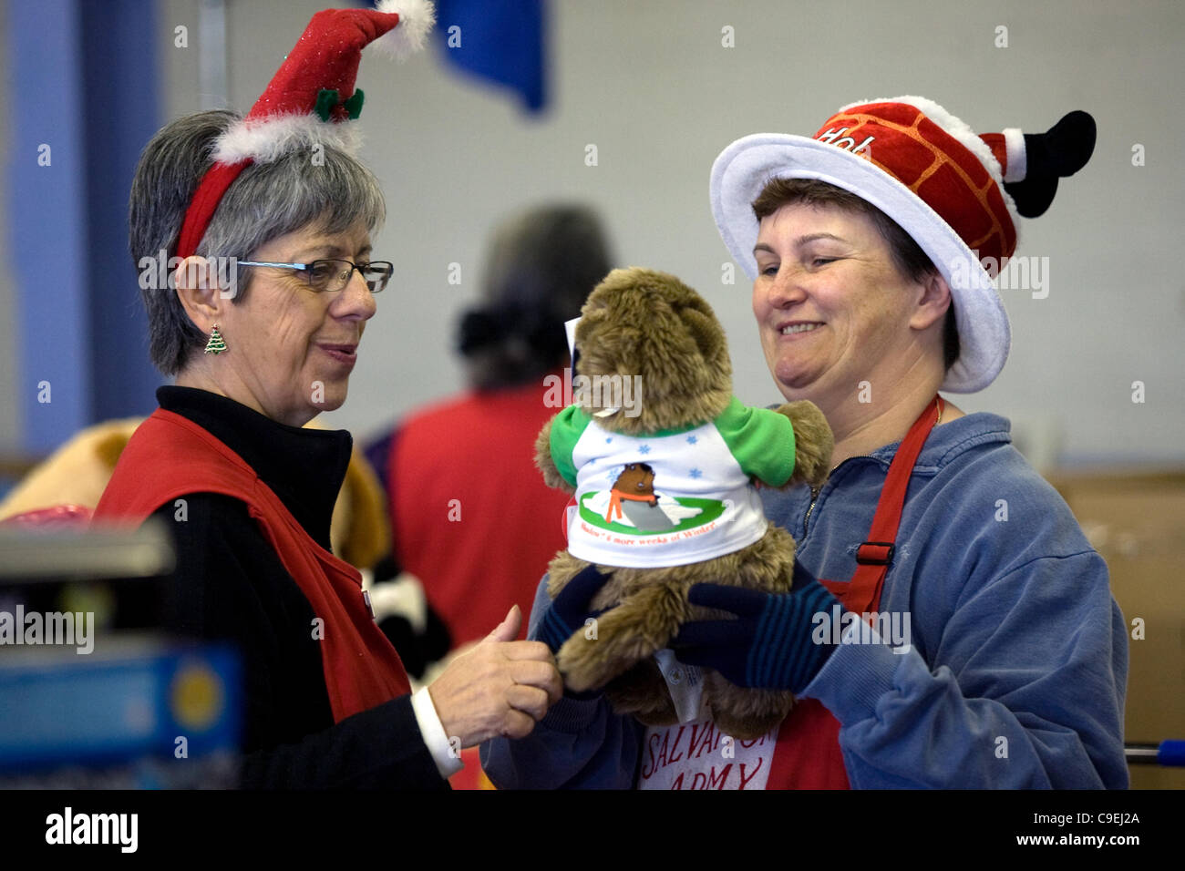 London Ontario, Canada - December 8, 2011. Cheryl Leyes, left and Kelley Thompson take a minute out from packing Christmas hampers to enjoy a donated toy at the 2011 Salvation Army toy and food drive distribution centre inside the Progress Building at the Western Fair District. This year the Salvati Stock Photo