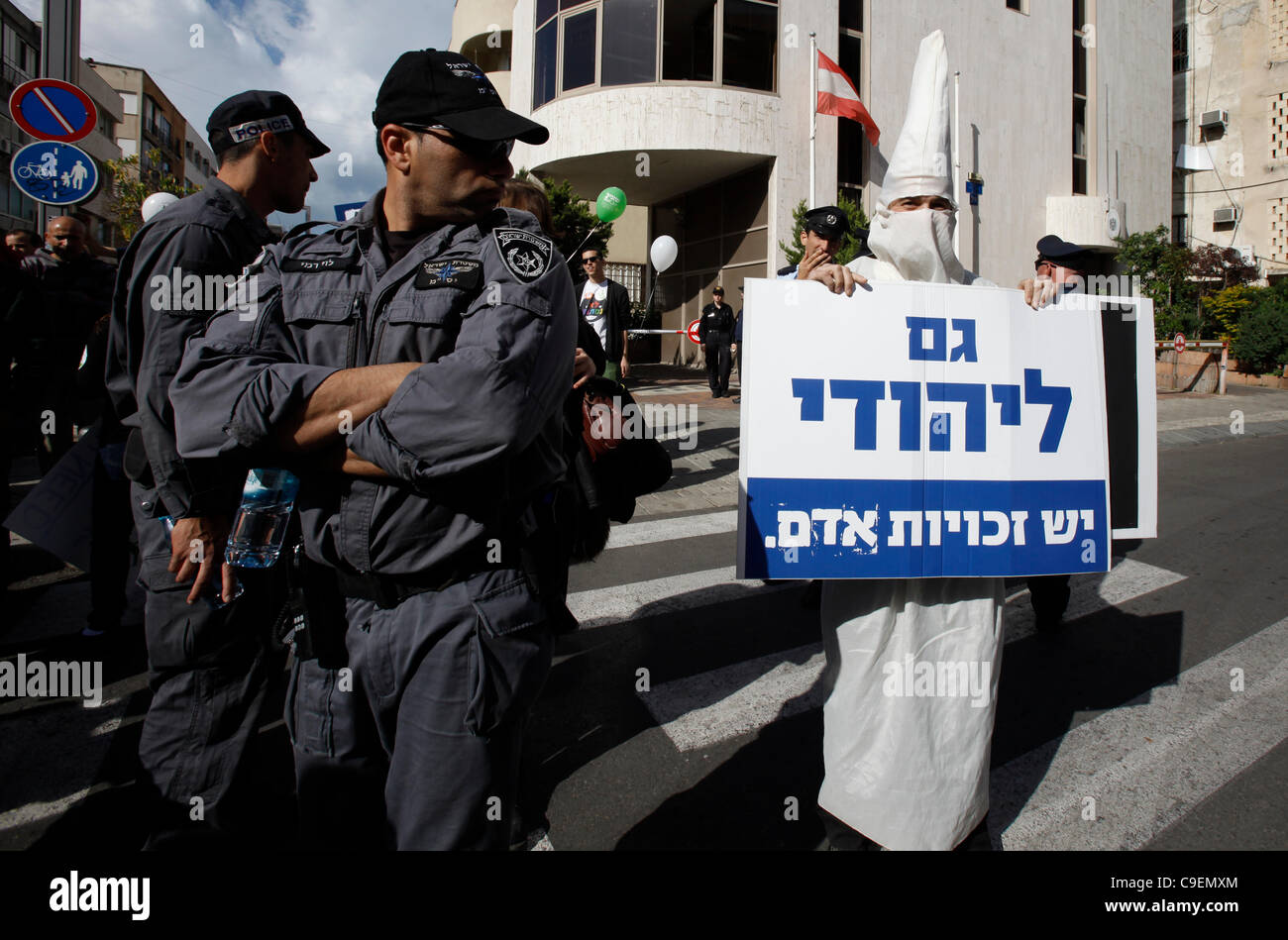A right wing supporter dressed as Ku Klux Klan KKK member holds a sign in Hebrew reading 'A Jewish person has also human rights' as thousands of people participated in a rally to mark the international Human Rights Day in Tel Aviv Israel Stock Photo