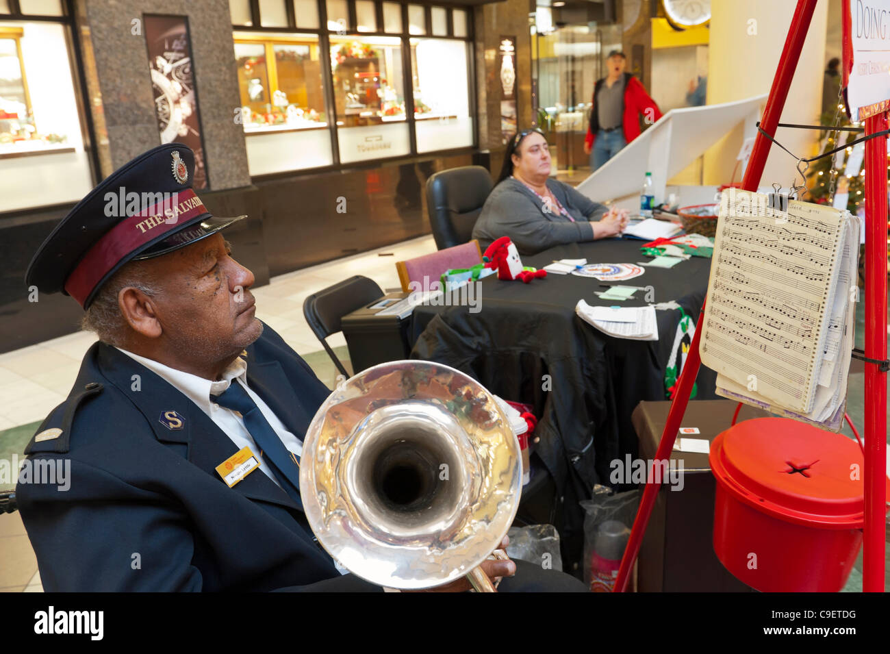 GARDEN CITY, NY, USA - DECEMBER 09: Members of Salvation Army, a charitable and religious organization, raise funds and run Toy Drive at Roosevelt Field Shopping Mall, New York, on Friday, December 9, 2011. Trumpeter Neville Lyttle (left) played for their Red Kettle Christmas Campaign. Stock Photo