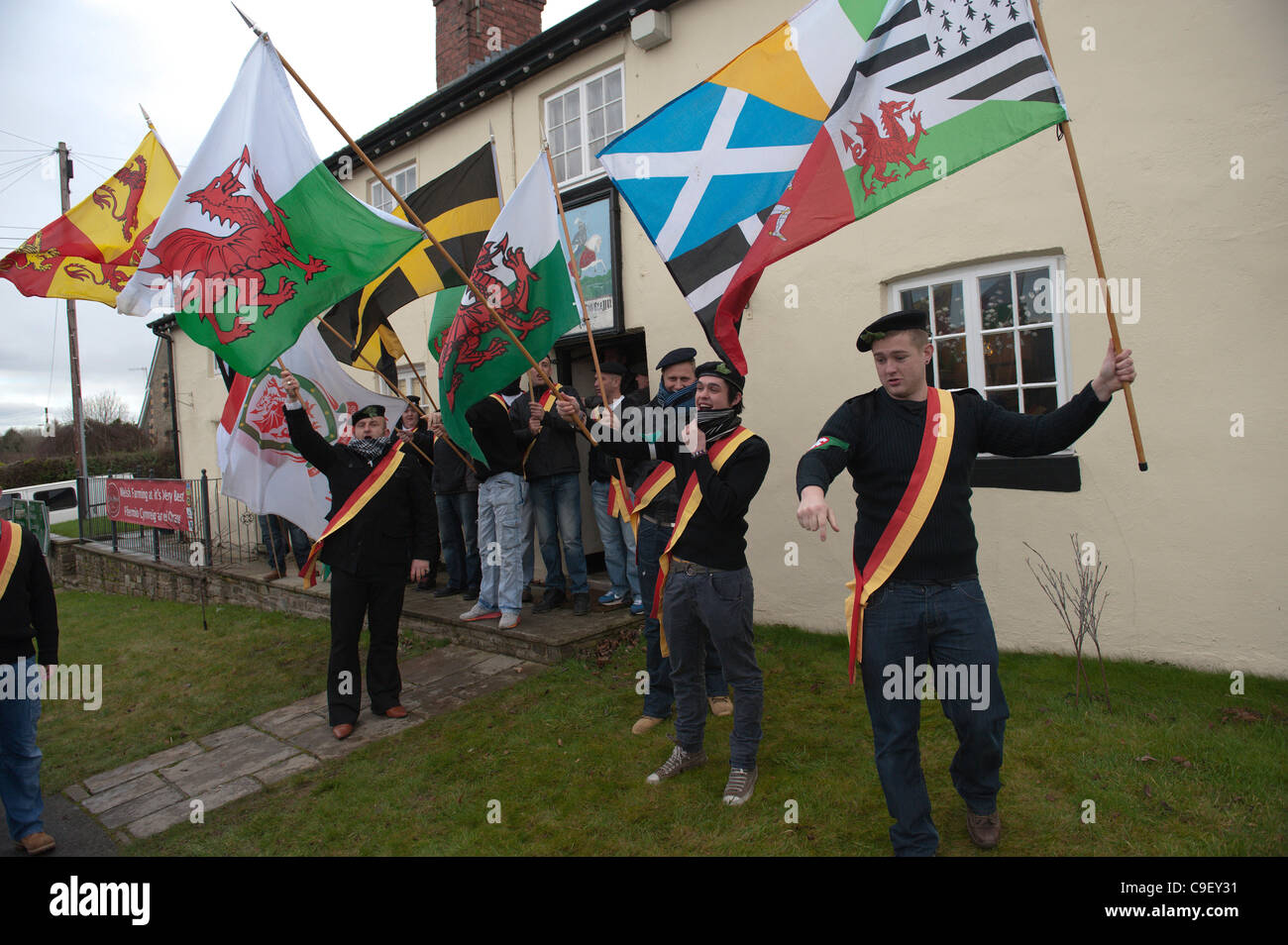 Welsh Nationalists carrying flags of the Welsh ruler Owain Glyndwr are in good spirits as they wait outside The Prince Llywelyn Inn for the start of the march to the Memorial Stone - Wales UK. Stock Photo