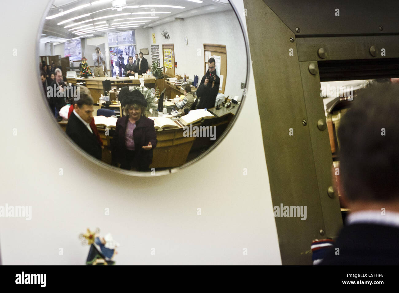 Dec. 14, 2011 - Harlan, Iowa, U.S. - Republican presidential candidate Texas Gov. Rick Perry is reflected in a mirror as he talks with small business owner Randy Ouren and Dawn Cundiff of the Shelby County Chamber of Commerce in an old bank vault used to maintain property titles and records as he ca Stock Photo