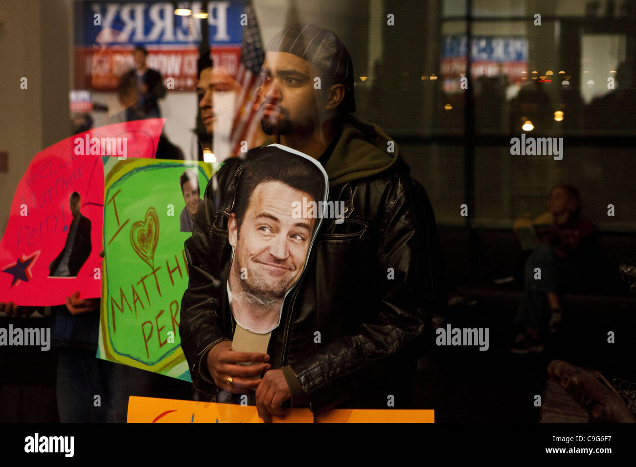 Dec. 20, 2011 - Davenport, Iowa, U.S. - People hold up signs with faces of Matthew Perry from the ''FRIENDS'' television show - satirically claiming they thought Matthew Perry and Chandler were supposed to visit - while Republican presidential candidate Texas Gov. Rick Perry speaks during a campaign Stock Photo