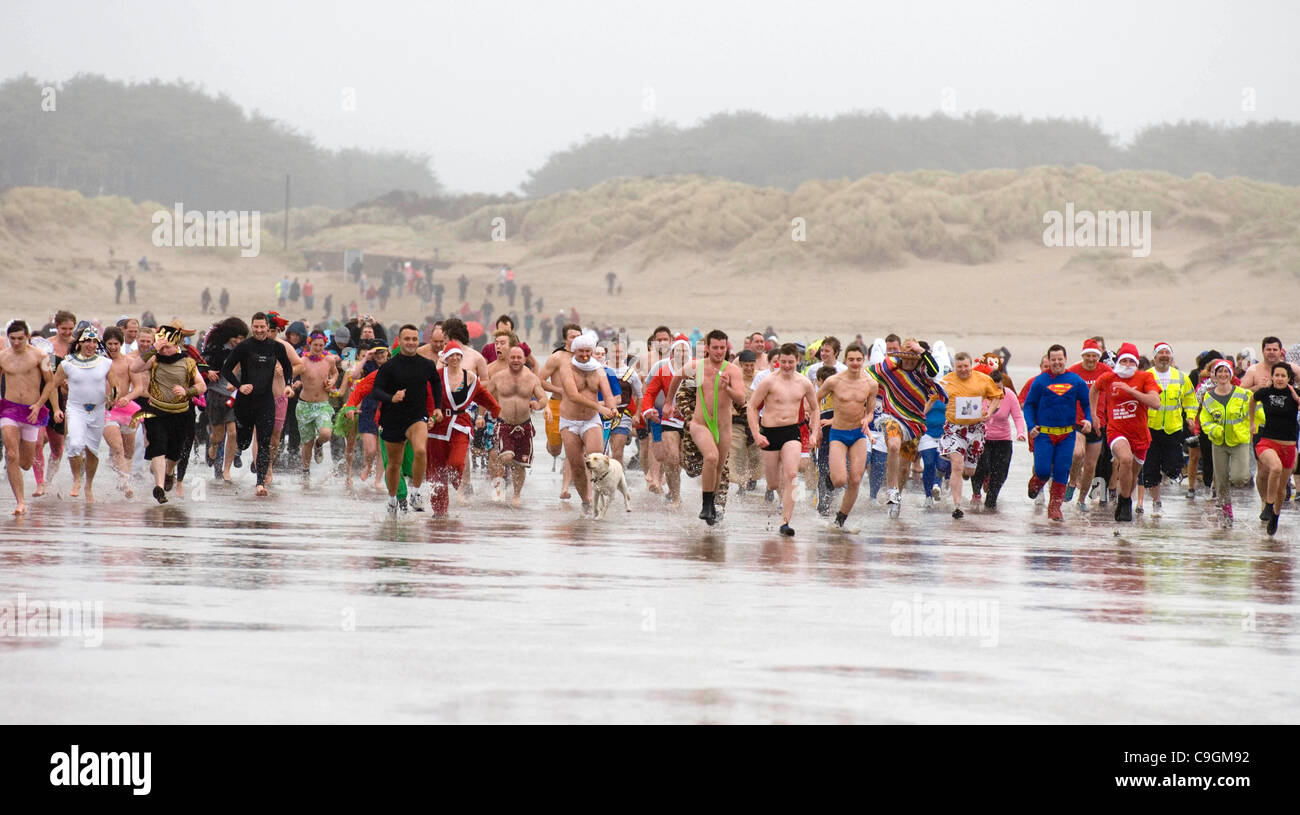 Pembrey, Llanelli, UK. 26th Dec, 2011. Swimmers racing into the sea at the annual Boxing Day 'Walrus Dip' at Cefn Sidn beach in Pembrey near Llanelli today. The leading runner at the front is wearing a mankini. Stock Photo