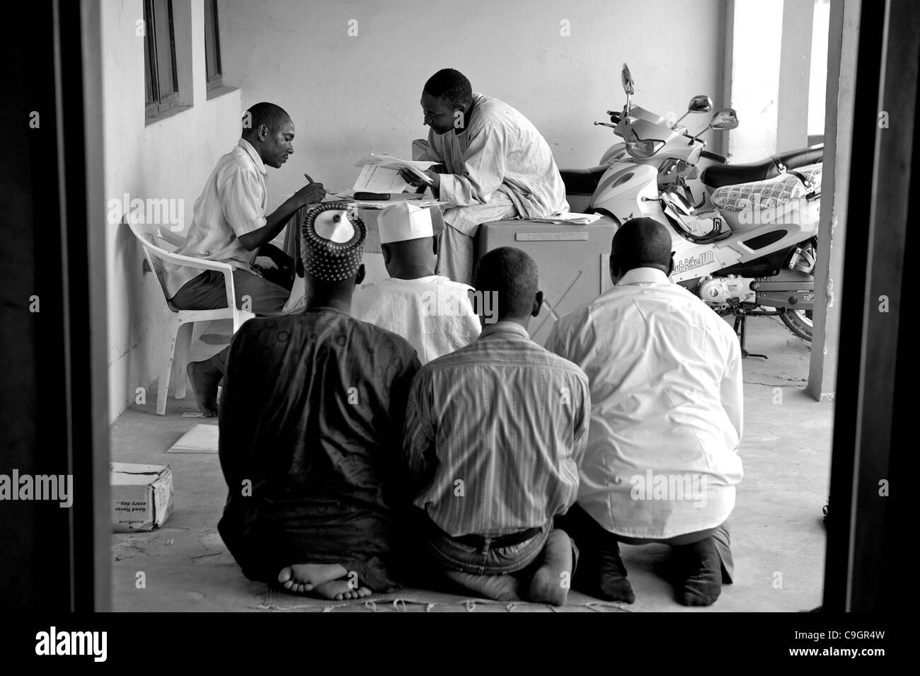 Sept. 18, 2010 - Kura, KANO, NIGERIA - While men break to pray, Ward Kwciri IPD focal person Auwalu Sulaiman seated, counts tallies at the end of day one of the immunization campaign. .Religious zealotry and misinformation have coerced villagers in the Muslim north of Nigeria into refusing polio vac Stock Photo