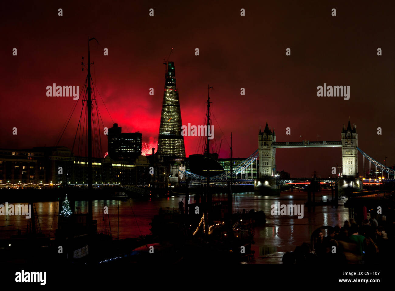 London Shard and Tower Bridge back-lit at night by New Years Eve fireworks display on River Thames Stock Photo