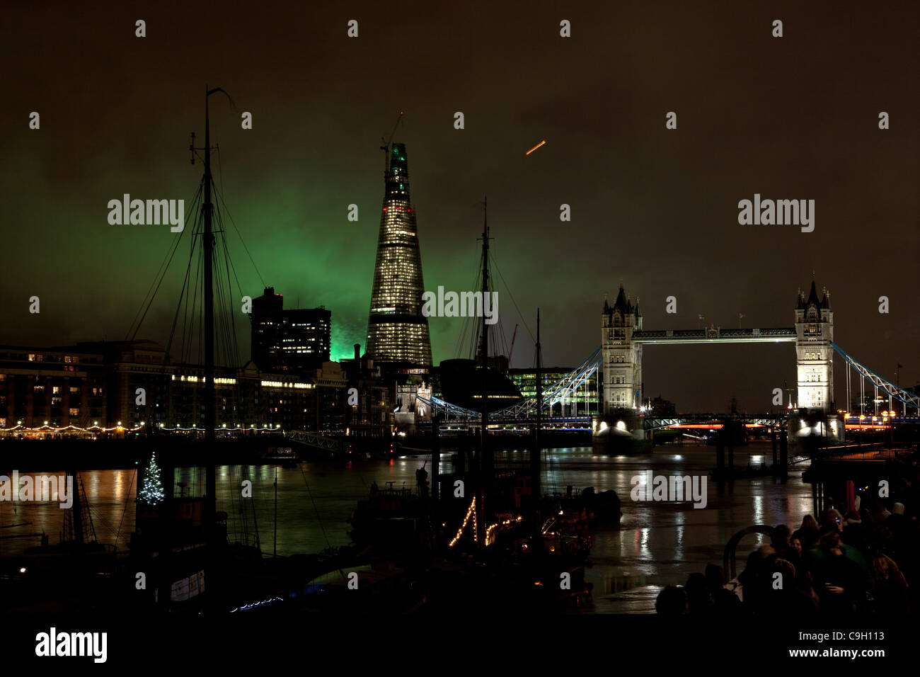 London Shard and Tower Bridge backlit at night by New Years Eve fireworks display on River Thames Stock Photo