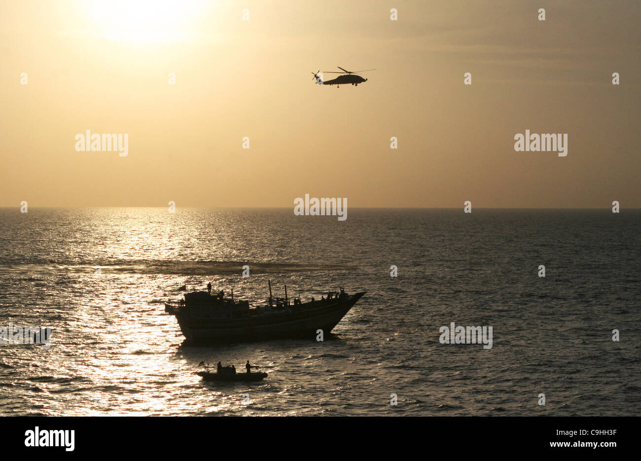 A US Navy Sea Hawk helicopter provides support to a visit, board, search and seizure team assigned to guided-missile USS Kidd alongside an Iranian fishing dhow Al Molai after responding to a distress call from the crew who was held captive by Somali pirates January 5, 2012 in the Arabian Sea. The Ki Stock Photo