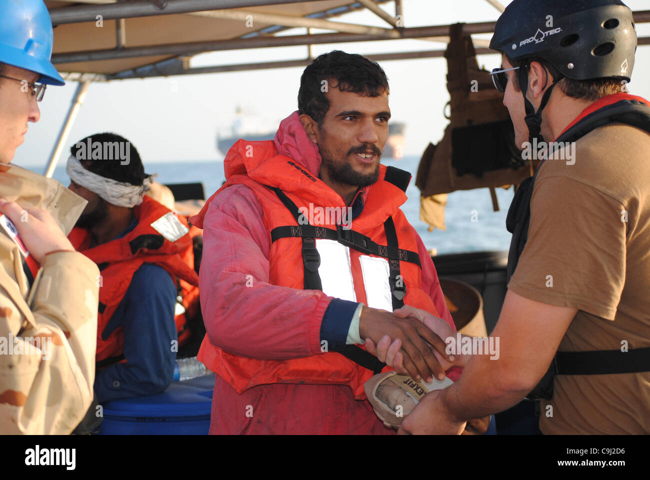 An Iranian sailor thanks a US Coast Guardsmen after the US Coast Guard Cutter Monomoy rescued six Iranian sailors who had to abandon their sinking dhow January 10, 2012 in the Arabian Gulf. The dhow, Ya-Hussayn, began sinking after its engine room flooded. Stock Photo