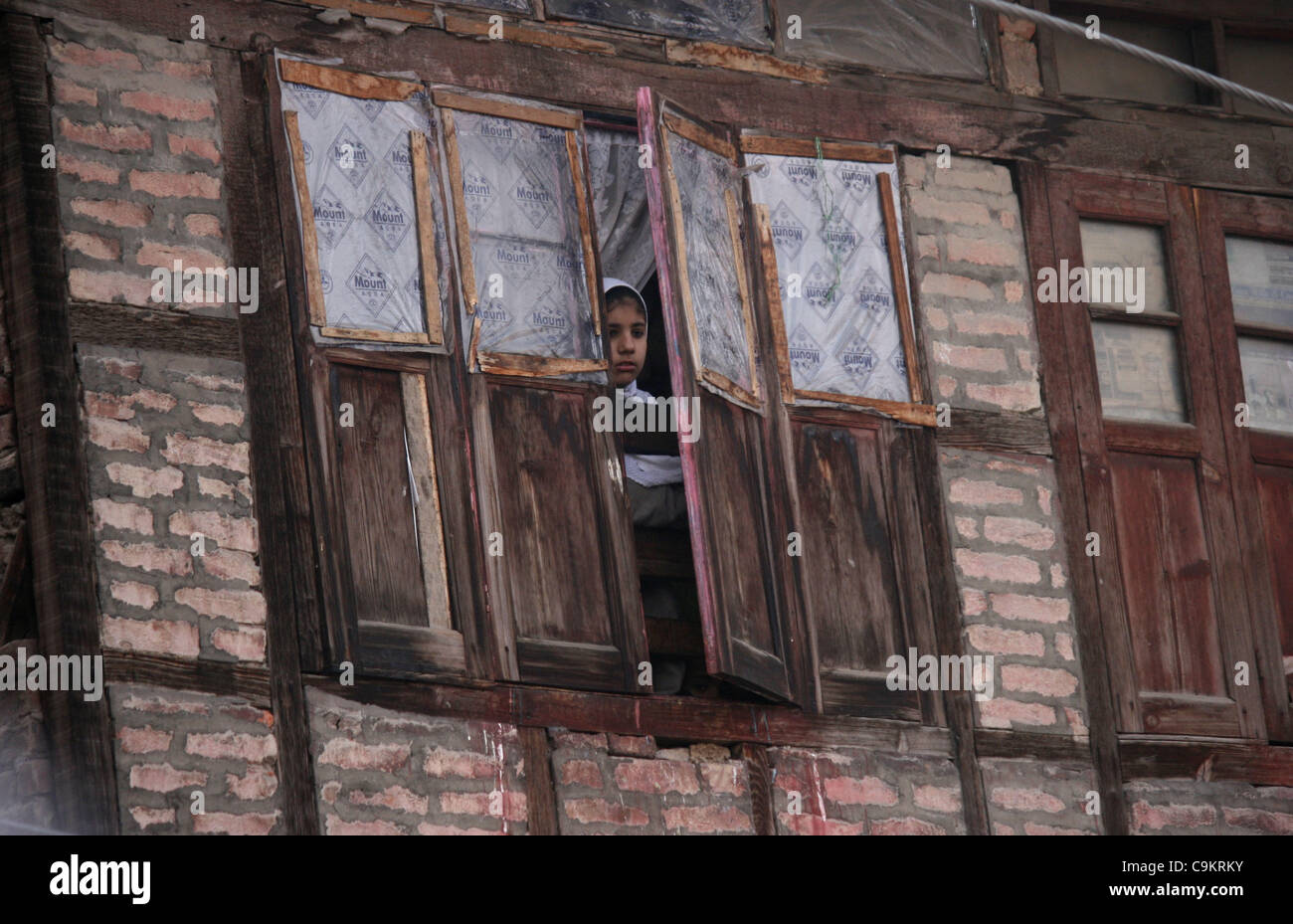 A kashmiri muslim girl watch from her windo during a   protest in Srinagar,the summer capital of indian kashmir on  Jan21, 2012. The protesters were marching towards the Gaw Kadal Bridge here when the police used batons to disperse them. The protests were part of the separatists programme to commemo Stock Photo