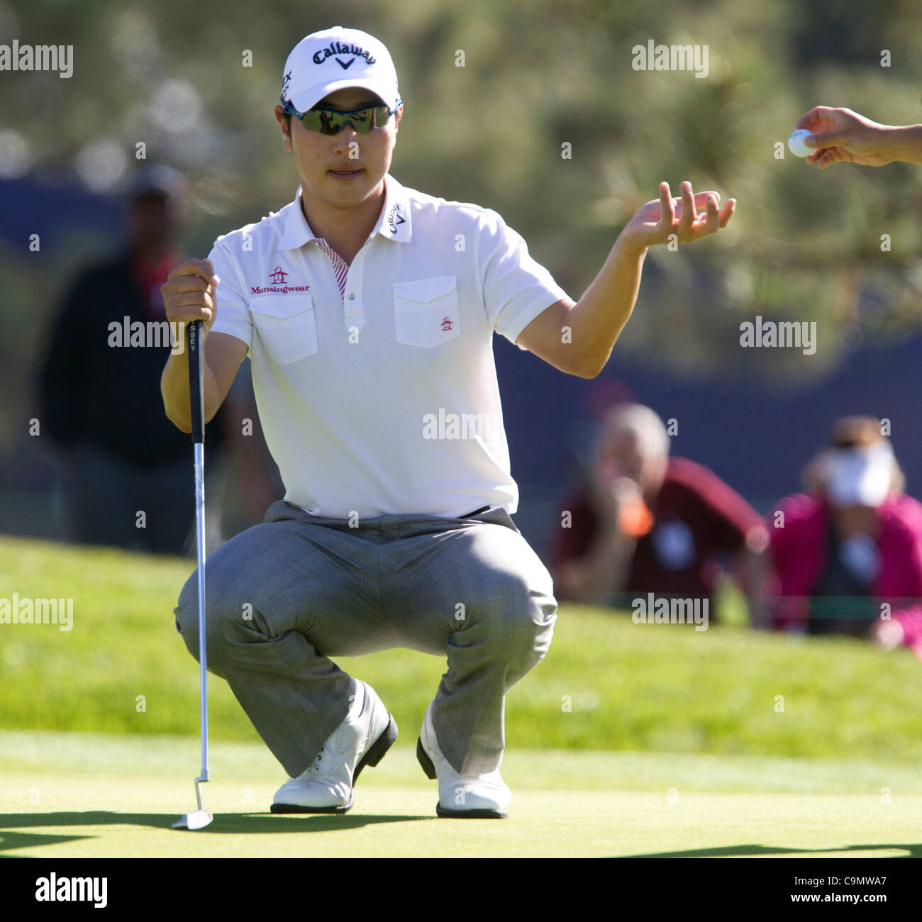 Jan. 27, 2012 - Sang-Moon Bae's caddy hands him his ball as Bae lines up his putt and goes 11 under at the south course 8th green during the Farmers Insurance Open at Torrey Pines on Friday. HAYNE PALMOUR IV | hpalmour@nctimes.com (Credit Image: © North County Times/ZUMAPRESS.com) Stock Photo