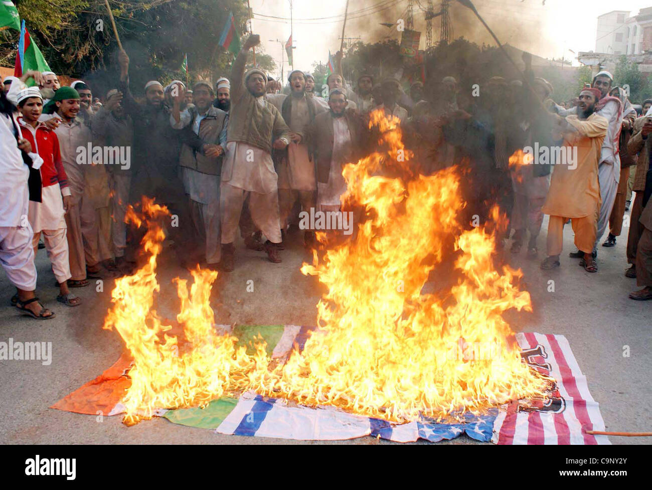 Supporters of Jamiat Talba Arabia (JTA) gather near burning Indian Israel and US flags chant slogans during Salmiat-e-Pakistan rally in Hyderabad on Friday, February 03, 2012. Stock Photo