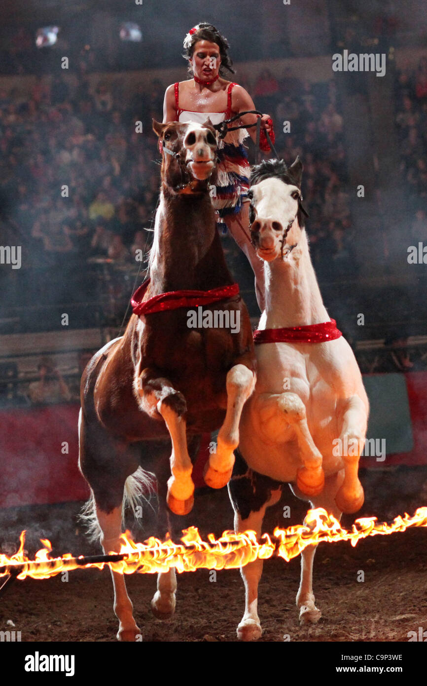 A trick rider leads two horses over a line of fire during the