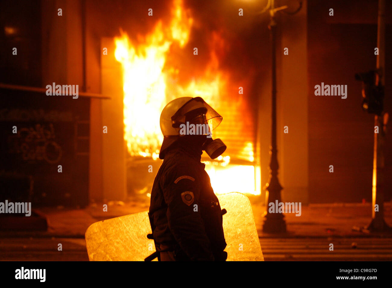 Feb. 12, 2012 - Athens, Greece - A riot policeman stands near a burning building set on fire during clashes as protesters fought with police, turning the center of Athens into a battle zone while lawmakers debated austerity measures. (Credit Image: © Aristidis Vafeiadakis/ZUMAPRESS.com) Stock Photo