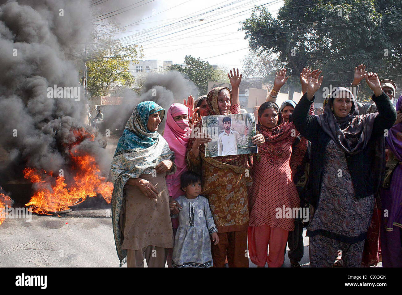 Women residents of Wazirabad Tehsil Gujranwala District gather near burning tyres as they are protesting against killing of Muhammad Shoaib, in Lahore on Monday, February 27, 2012. Stock Photo