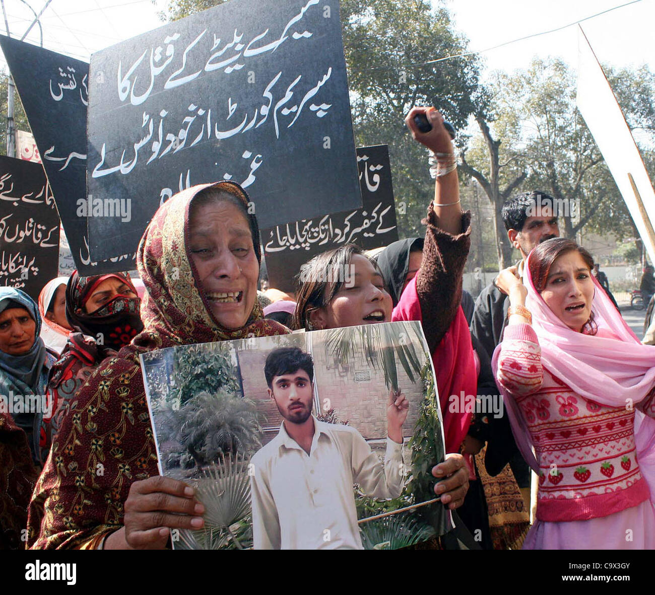 A woman resident of Wazirabad Tehsil Gujranwala District holds picture of Muhammad Shoaib as they are protesting against his killing, in Lahore on Monday, February 27, 2012. Stock Photo