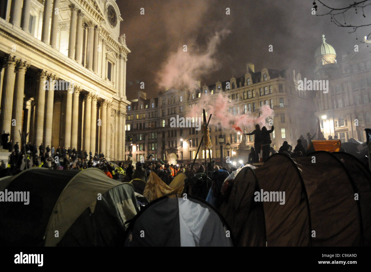 London, UK. 28/02/12. Protesters let of flares as riot police and ...