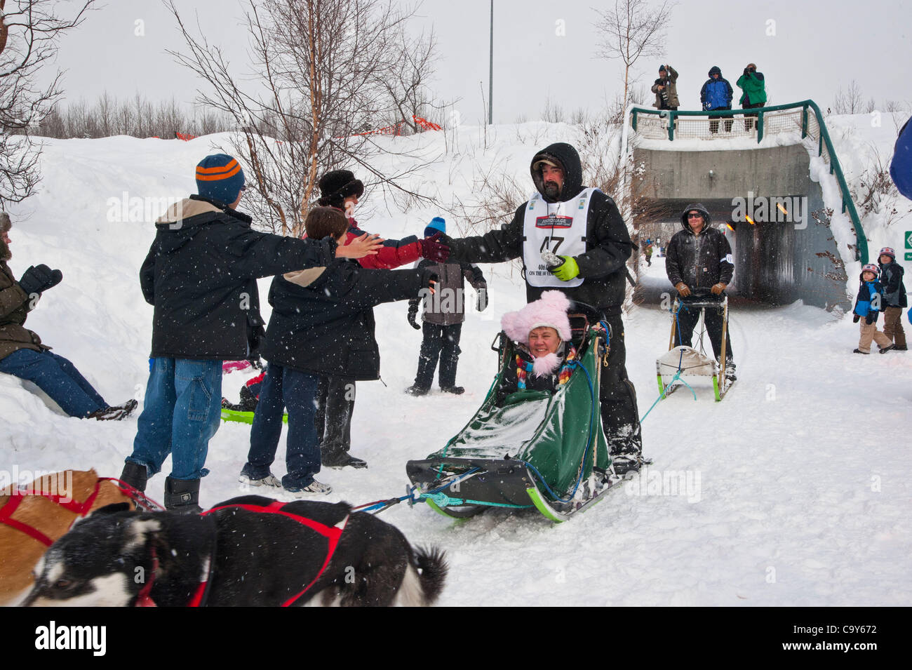 Musher  Kirk Barnum passes by spectators at Tudor Road during start of Iditarod 2012, Anchorage, Alaska, March 3, 2012 Stock Photo