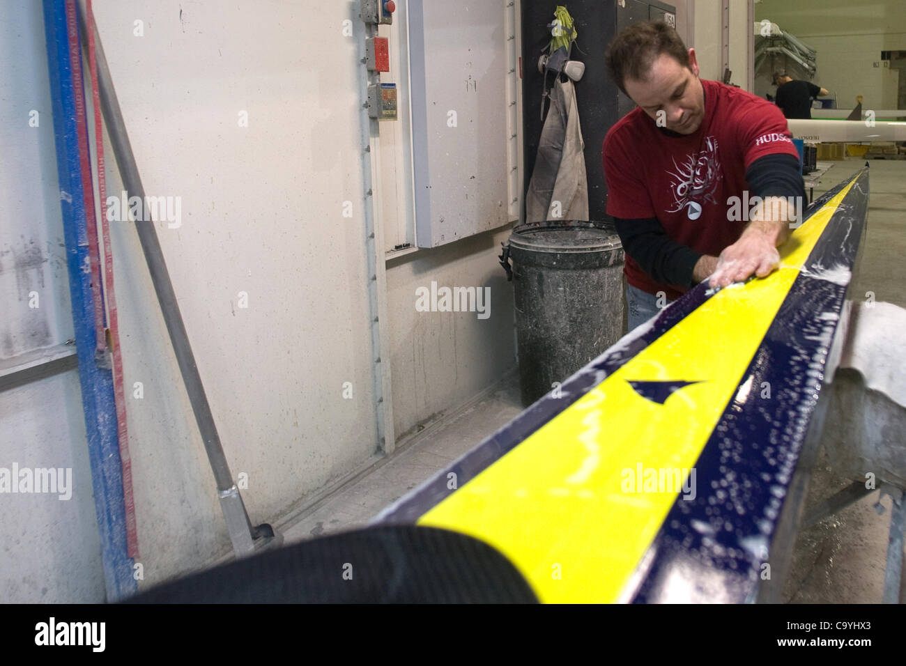 London Ontario, Canada - March 5, 2012. Steve Mann wet sands a shell that is painted in University of Michigan colours. Hudson Boat Works has been building high performance racing shells since 1981. Located in London Ontario, Canada the company supplies boats to National and Olympic teams around the Stock Photo
