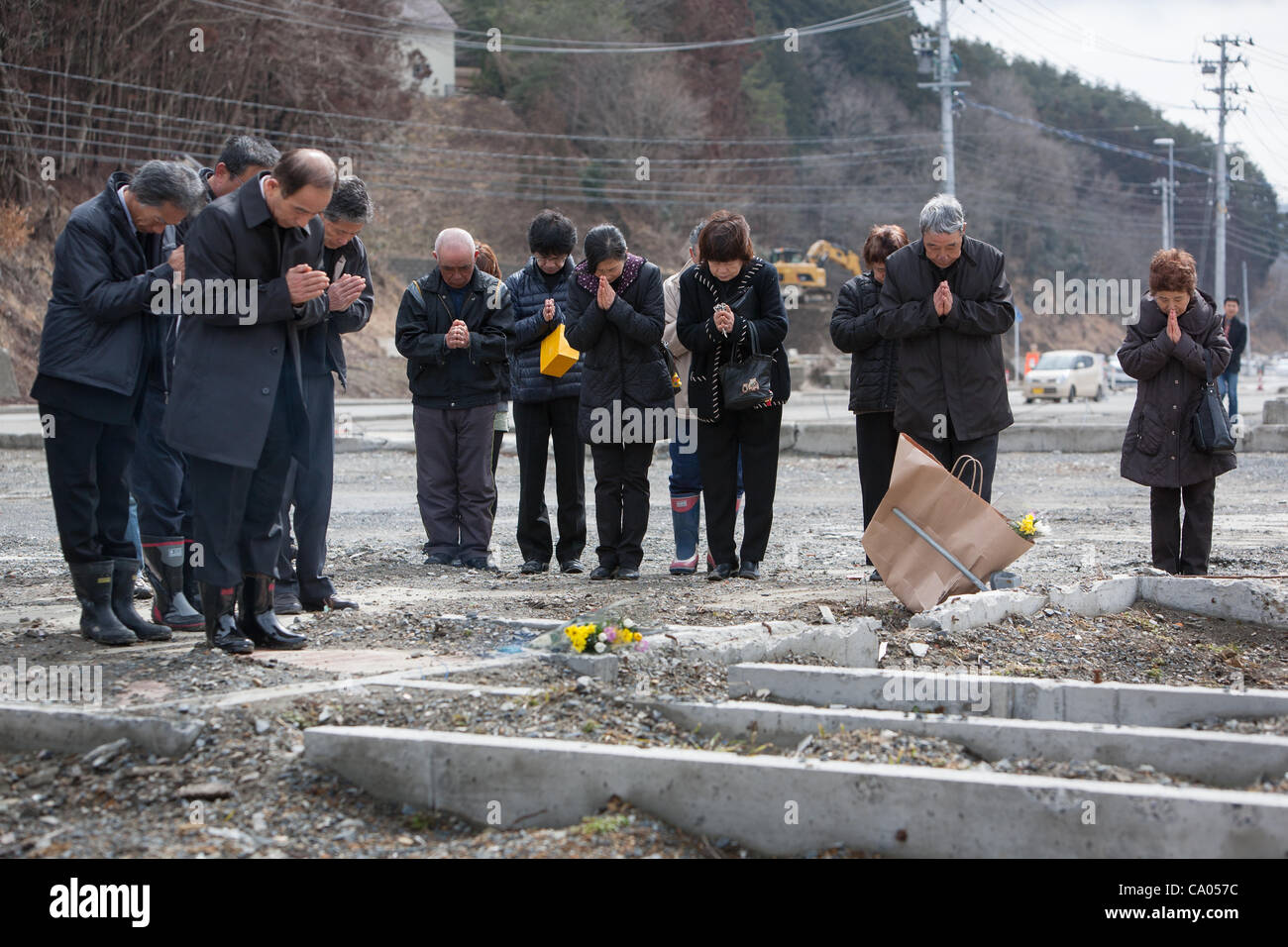 Former residents of Tennomae community lay flowers at make-shift shrines and pay their respects to the victims of the 2011 tsunami, and lament that their community now ceases to exist other than in spirit, on the 1 year anniversary of the March 11th 2011 earthquake and tsunami, in Minami-Sanriku, To Stock Photo