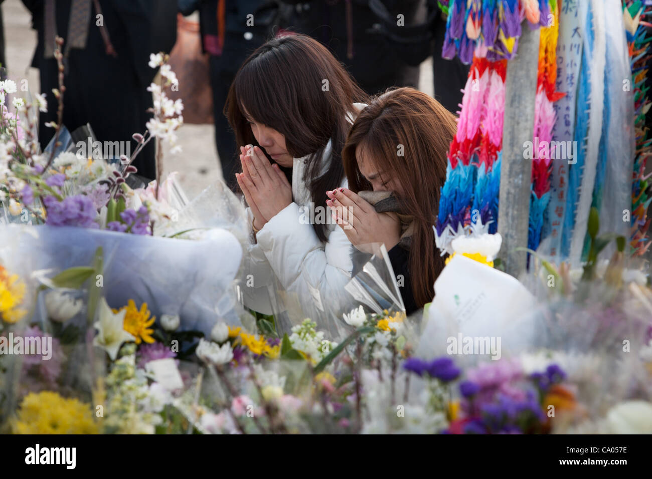 Teenage girls cry and pray at the shrine which stands beside Okawa Elementary School- a school in which 74 children and 10 teachers lost their life due to fatal indecision on the teacher's part on where to evacuate the children to after the earthquake hit but before the tsunami struck, on the 1 year Stock Photo