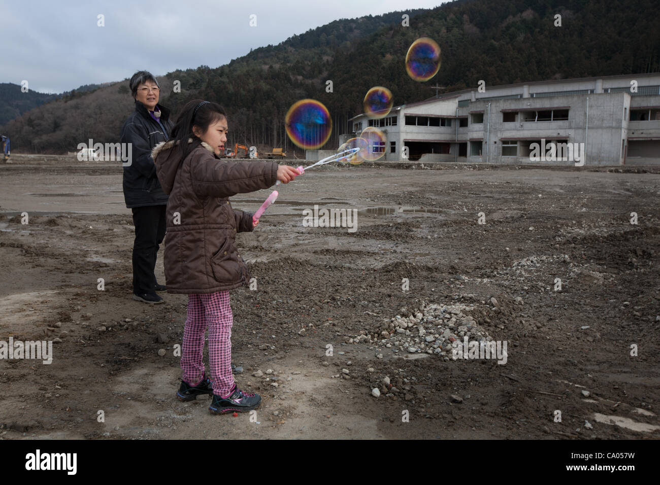 Hiroko Oyama and granddaughter Hikari release bubbles into the air ( 'as all children like bubbles') for the memories of the 74 children who lost their lives at Okawa Elementary School, in the muddy plain where once stood the community of Kamaya, on the 1 year anniversary of the March 11th 2011 eart Stock Photo