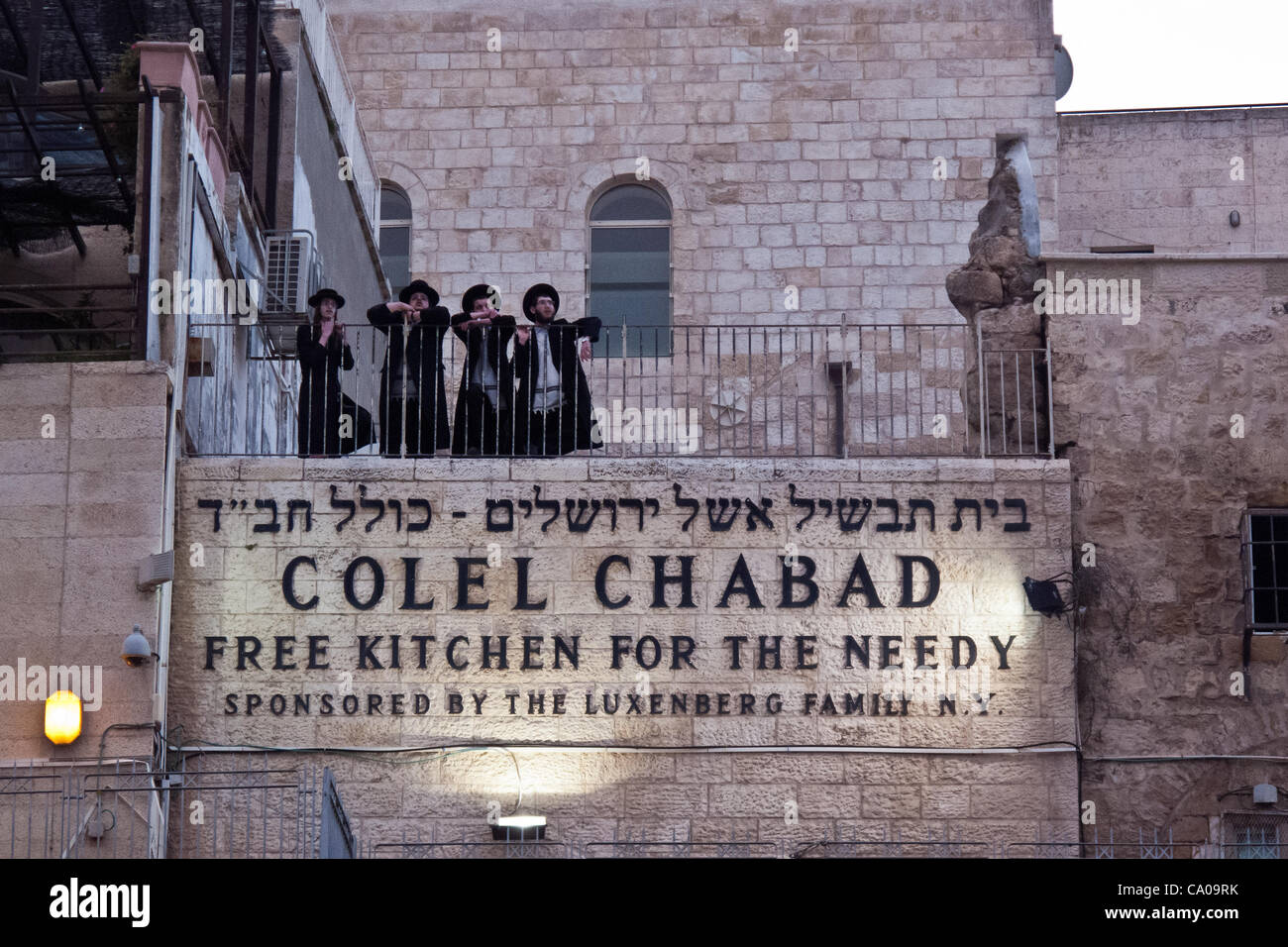 Ultra-Orthodox Jewish men stand on a balcony in the Jewish Quarter and view a welcoming ceremony for thousands of swifts returning from South Africa to nest in the Western Wall as spring and breeding season arrive. Jerusalem, Israel. 12-Mar-2012. Stock Photo