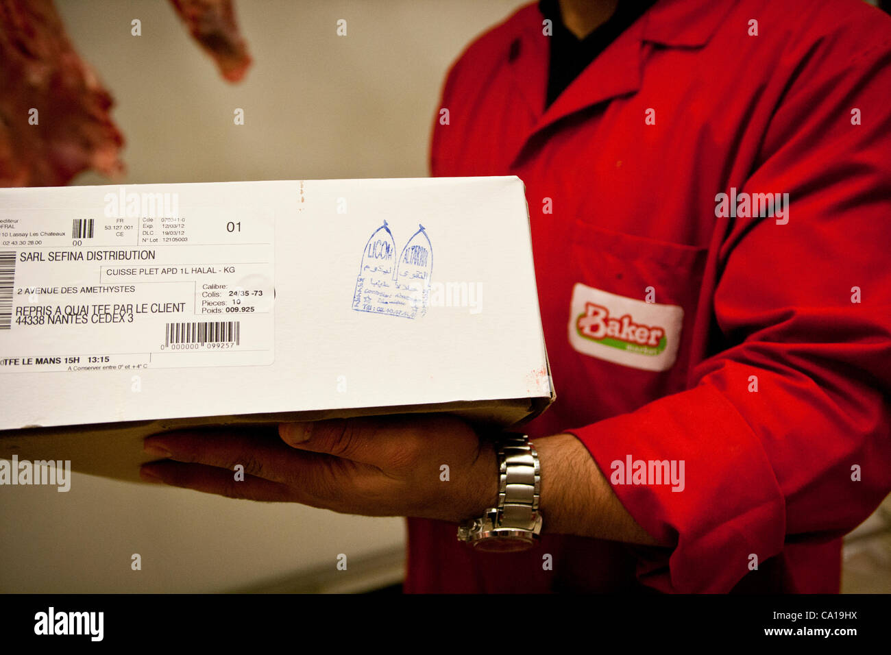A butcher shows a stamp showing that a box of meat products is Halal, at a Halal supermarket in Nantes, France, 17 March 2012 Stock Photo
