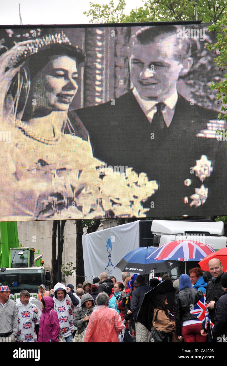 3rd June 2012. Victoria Embankment, London, UK. A big screen shows the wedding of Queen Elizabeth and Prince Phillip as the crowds flood down to the embankment early in the morning to prepare to see the Pageant on the Thames. Stock Photo