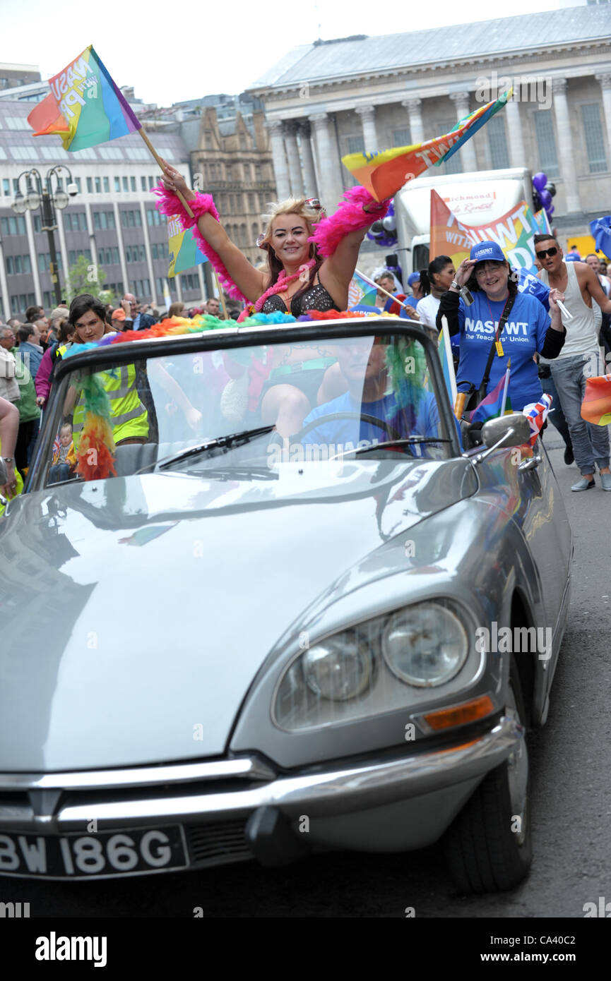 Blonde woman waving rainbow flags wearing a bra sitting on the back of a convertible grey Citroen DS in Birmingham Pride parade Stock Photo
