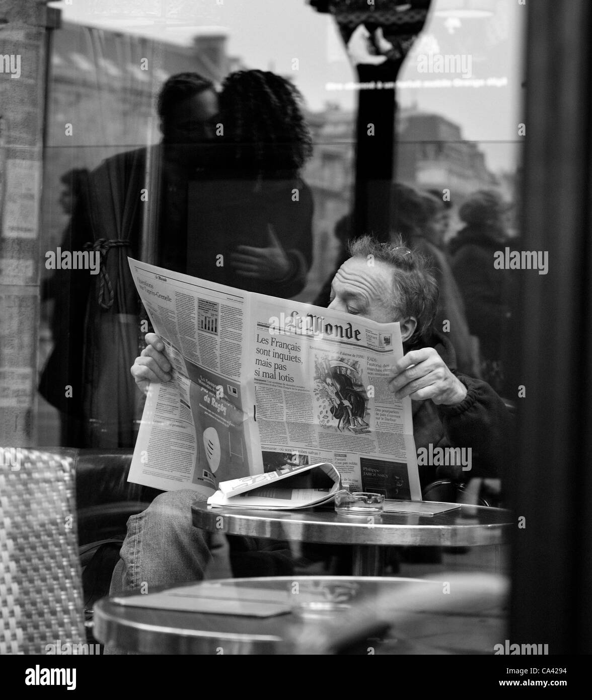 Nov 01, 2007 - Paris, France - Man in a cafe reads the newspaper Le Monde as a couple embracing is reflected in the glass, Saint Severin Cafe, Place St. Michel. (Credit Image: (c) Mark Avery/ZUMA Press) Stock Photo