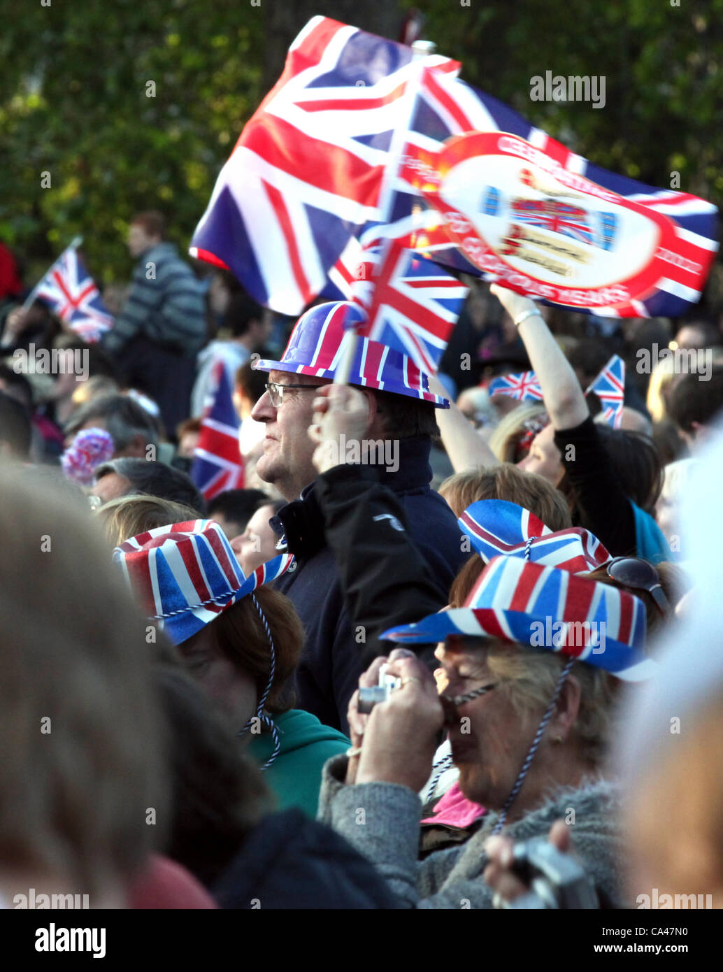 London, UK. June 4, 2012. Patriotic fans enjoy the Concert to celebrate The Queen's Diamond Jubilee on the big screens in St. james's Park, with Union Jack flags and hats. Stock Photo