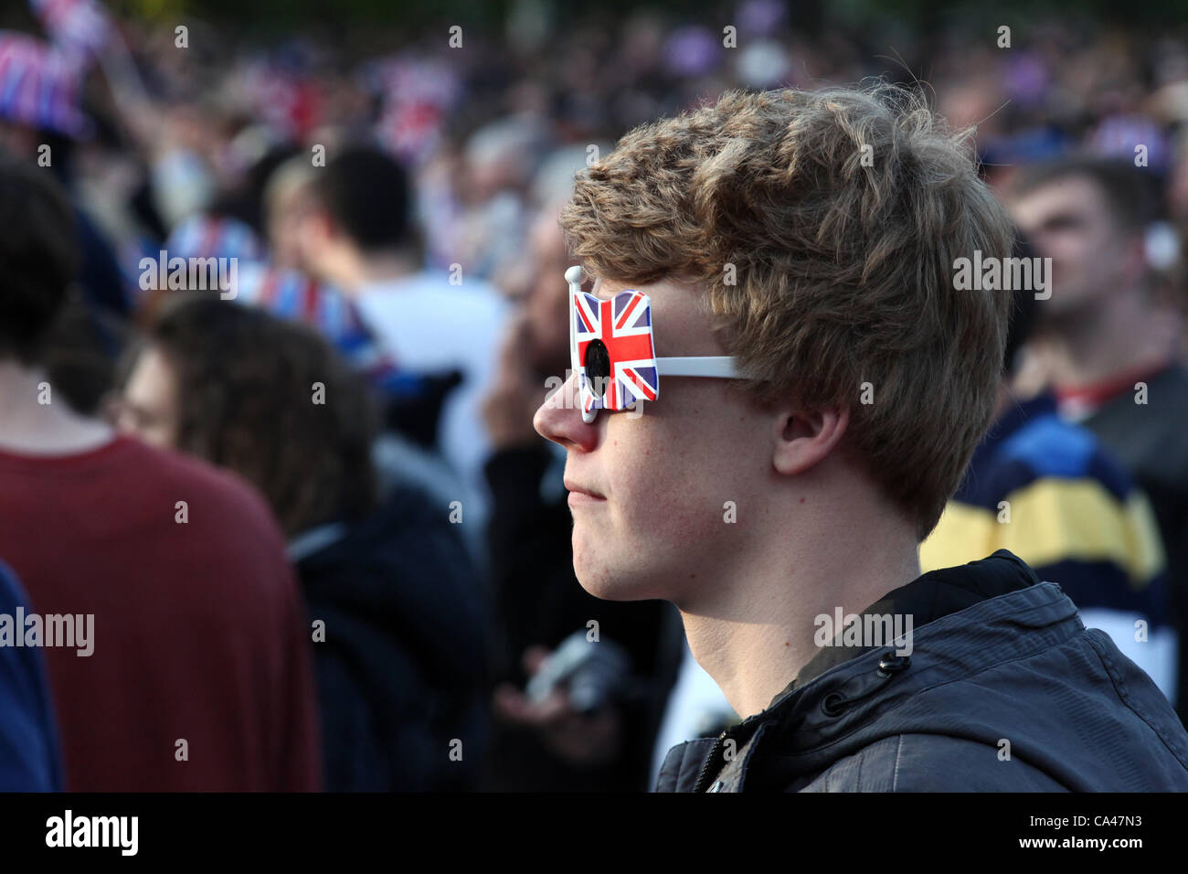 London, UK. June 4, 2012. One fan enjoys the Concert to celebrate The Queen's Diamond Jubilee on the big screens in St. james's Park, wearing Union Jack glasses! Stock Photo