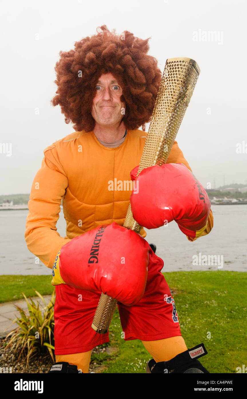 Larne, 07/06/2012 - A circus performer dressed as a boxer holds an Olympic Torch. Stock Photo