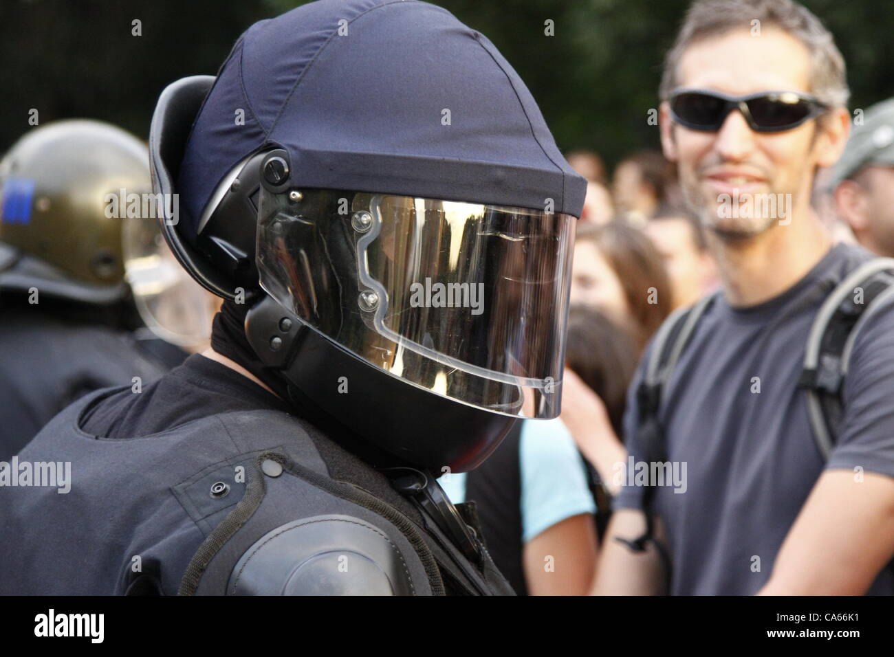Policeman in full riot gear and smiling demonstrator during the anti-government rally in Sofia. Thousands protested the change in the Bulgarian Forrestry Act that allows cutting down trees without changing the status of the land first. Sofia, Bulgaria, 14/06/2012 Stock Photo