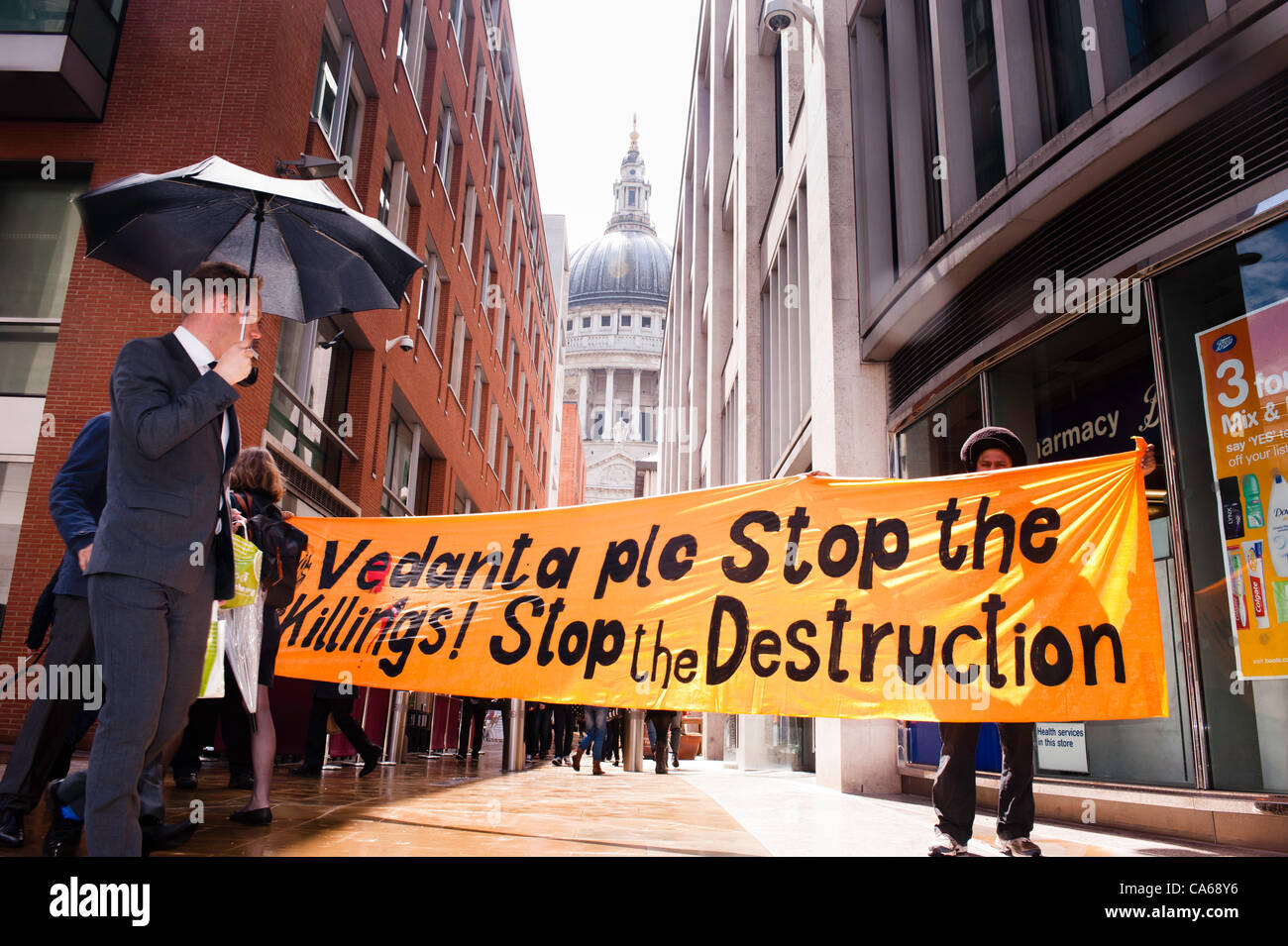 London, UK - 15 June 2012: protesters holding a banner reading ' Vedanta plc stop the killings! Stop the destruction' during the Carnival of Dirt. St. Paul's cathedral in the background. More than 30 activist groups have gathered to highlight the alleged illicit deeds of mining companies. Stock Photo