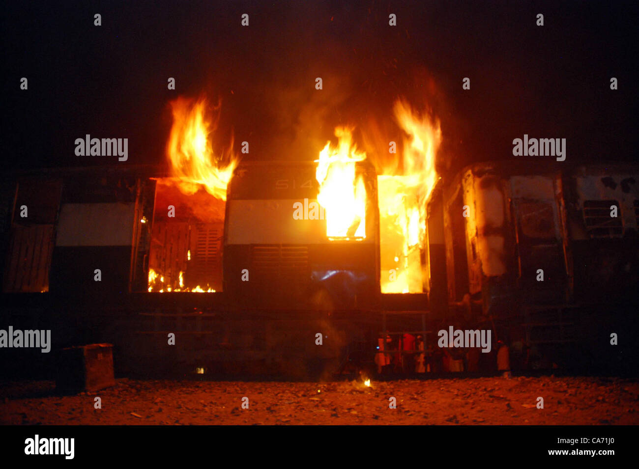 Fire flames rise from burning boogie of a passenger  train, which was set ablaze by angry protester, during protest demonstration residents of  Gujranwala against electricity load-shedding at Kamoke on last night, June 19, 2012. Stock Photo