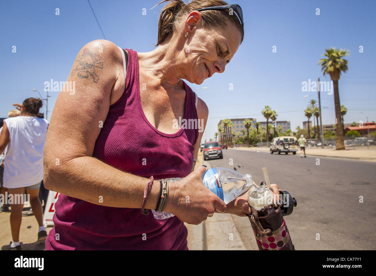 June 20, 2012 - A homeless woman pours water into her bottle in Phoenix,  AZ, Wednesday. June 20 is the first day of summer in the northern  hemisphere. The high temperature in