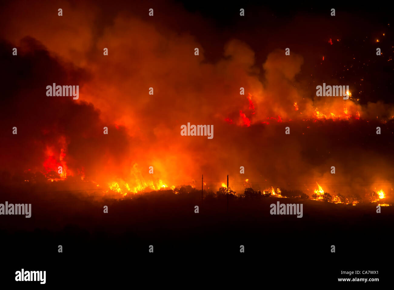 Forest fire rages with intense flames and smoke during night in central Utah. Wood Hollow blaze on edge of rural community of Fountain Green. Fire spreads across many miles if dry drought  stricken grass, shrubs and trees. Several structures and cabins have been destroyed. Area has many cattle, shee Stock Photo