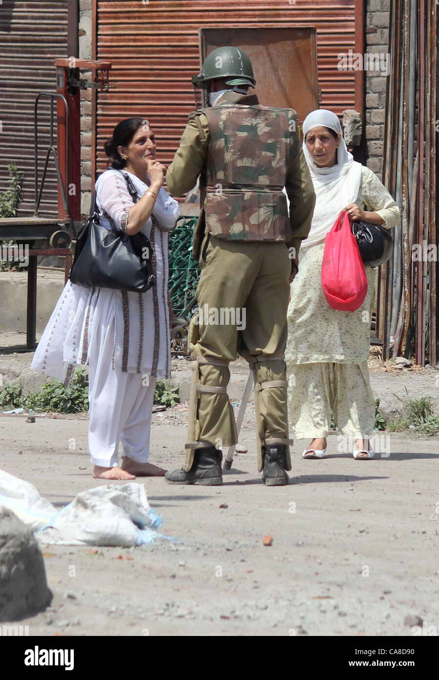 An Indian police questioning a Kashmiri Muslim woman during a curfew in downtown area of Srinagr, the summer capital of Indian Kashmir, 26, June, 2012,Undeclared curfew-like restrictions were imposed in the old city areas of Srinagar Tuesday following tension in the city over the gutting of the revered shrine of Sheikh Abdul Qadir Jeelani in the Khanyar area.Although no official announcement to this effect was made, police and paramilitary Central Reserve Police Force (CRPF) deployed in riot control gear disallowed pedestrian and vehicular movement in old city areas falling under the Khanyar,  Stock Photo
