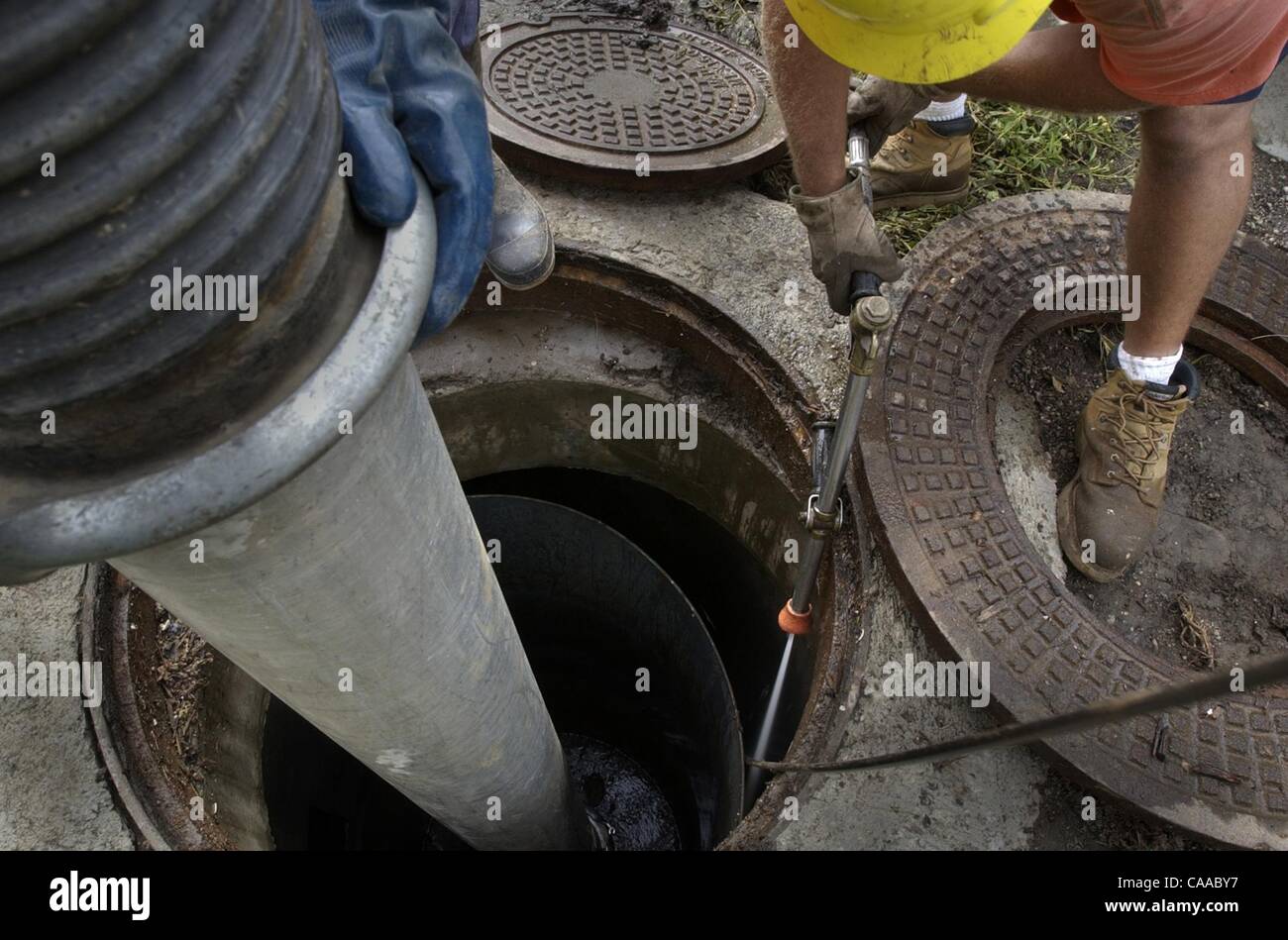 (Published 10/20/2004, NI-2) Workers use a vacuum device to remove debris from an oil-water separator in Vista on Lado de Loma Drive.  Recent rains and blockages caused the street to flood Sunday.  UT/John Gastaldo Stock Photo