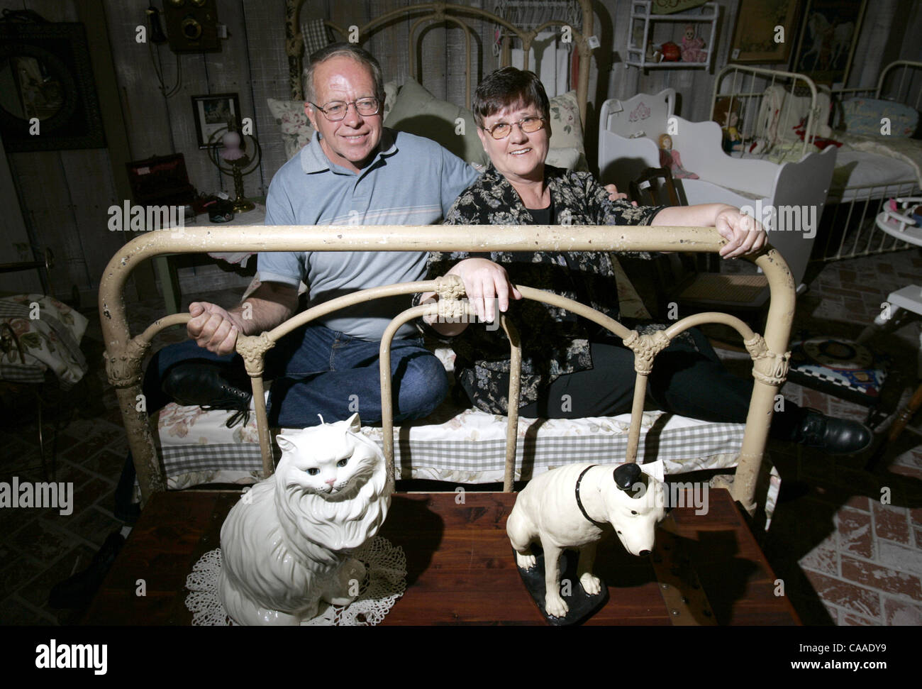 Bill and Carol Kearney, antique appraisers, sit on a vintage iron bed at Fourth Street Antiques