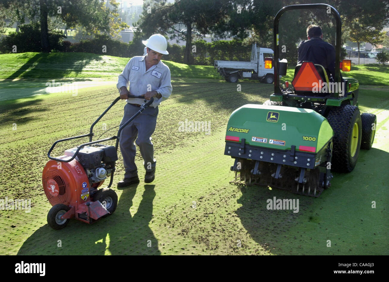 (PUBLISHED 09/25/2001, D-4) - SLaerification176764x001/Sept 24---At left Miguel Hernandez uses a blower to move the cores into a pile for removal after Martin Gonzalez passes by on the tractor which aerifies the 14th putting green at Carmel Mountain Ranch golf course. Photo/Scott Linnett Stock Photo