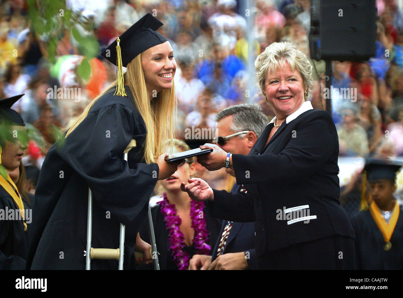 A graduate on crutches receives her diploma from the scool board
