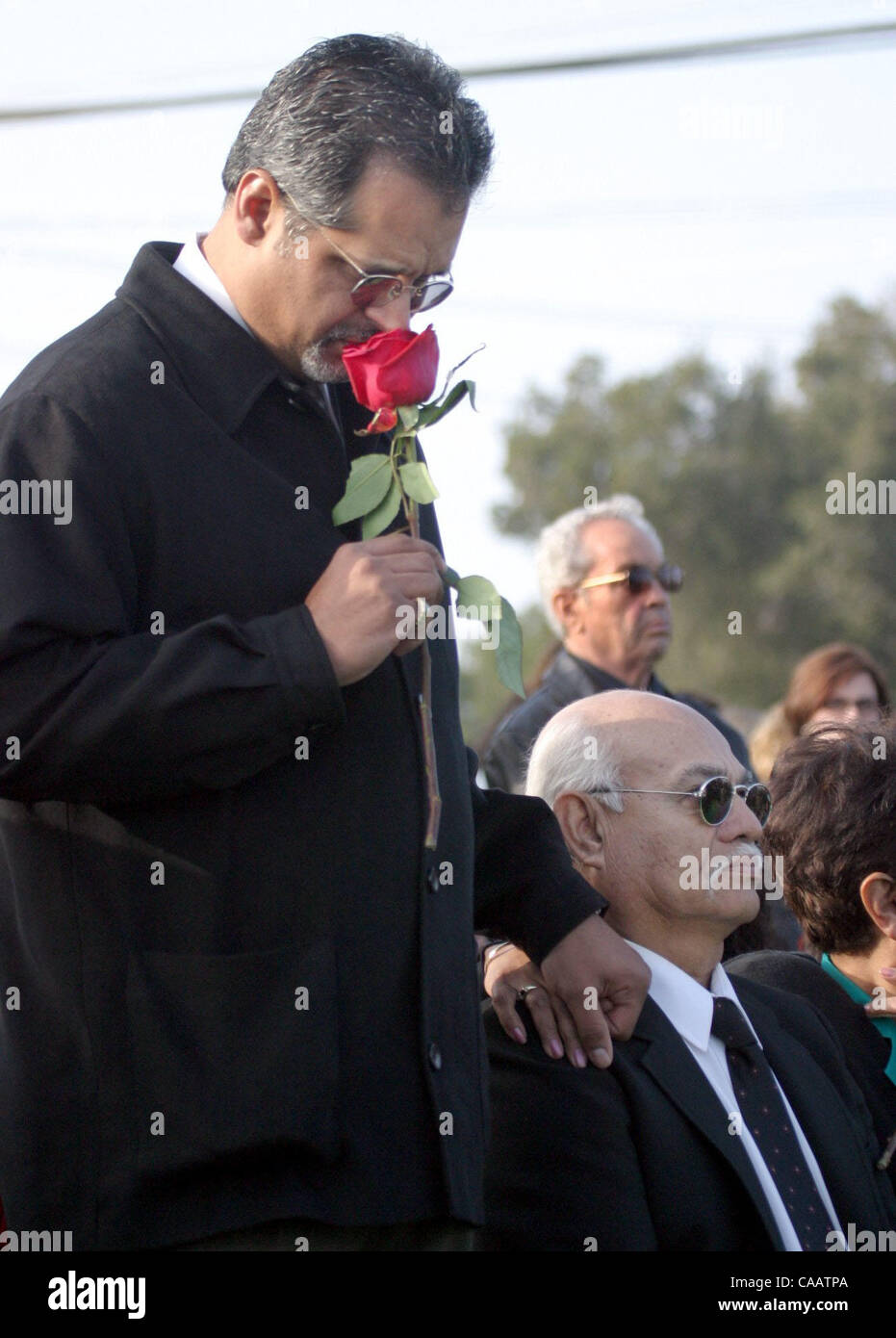 Michael Clement cq holds a rose during funeral services for his cousin Christopher Armstrong, who was 24 years-old, and his aunt Mary Helen Armstrong at Holy Cross Cemetery in Antioch, Calif. on Thursday, January 29, 2004. Clement's hand is on the shoulder of Mary Armstrong's brother Louis Orozco cq Stock Photo