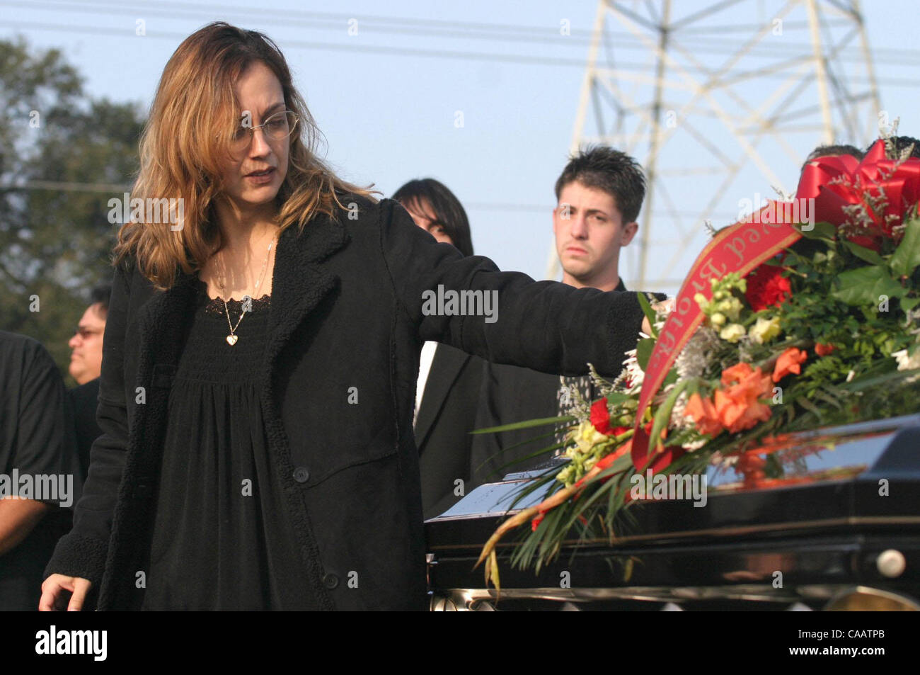 Erica Aguilar cq (left) stands near the casket of her brother Christopher Armstrong during funeral services for Christopher, who was 24 years-old, and his mother Mary Helen Armstrong at Holy Cross Cemetery in Antioch, Calif. on Thursday, January 29, 2004.  Mary, Christopher and Mary's husband Gary w Stock Photo