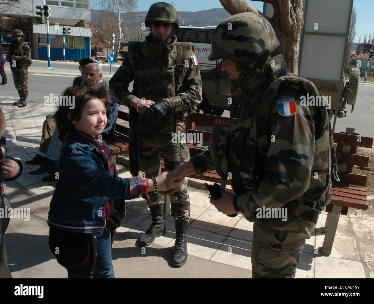 Mar 22, 2004; Kosovo, SERBIA; A French soldier, part of NATO-led peacekeepers in Kosovo (KFOR), shakes the hand of a Serbian girl in front of the bridge in Kosovska Mitrovica, that divides this troubled city into North (controlled by Serbs) and South (controlled by Albanians). Riots broke out in at  Stock Photo