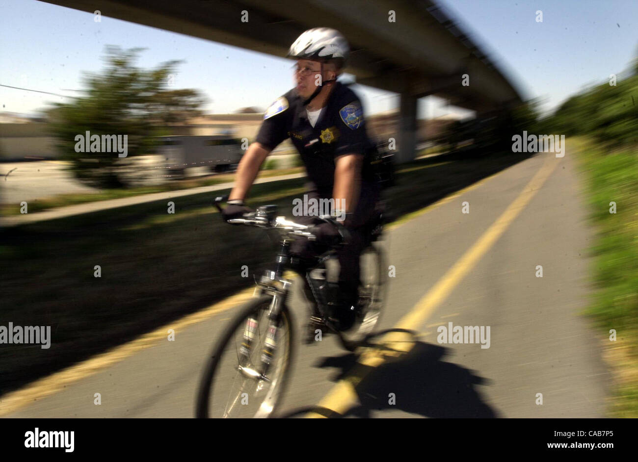 On a Mongoose mountain bike El Cerrito police officer Gilbert Tang (cq)patrols a stretch of trail under the BART tracks near El Cerrito Plaza in El Cerrito, Calif. on Wednesday, May 12, 2004. Tang rides the trail 3-4 times per week. (Contra Costa Times/Sherry LaVars) Stock Photo