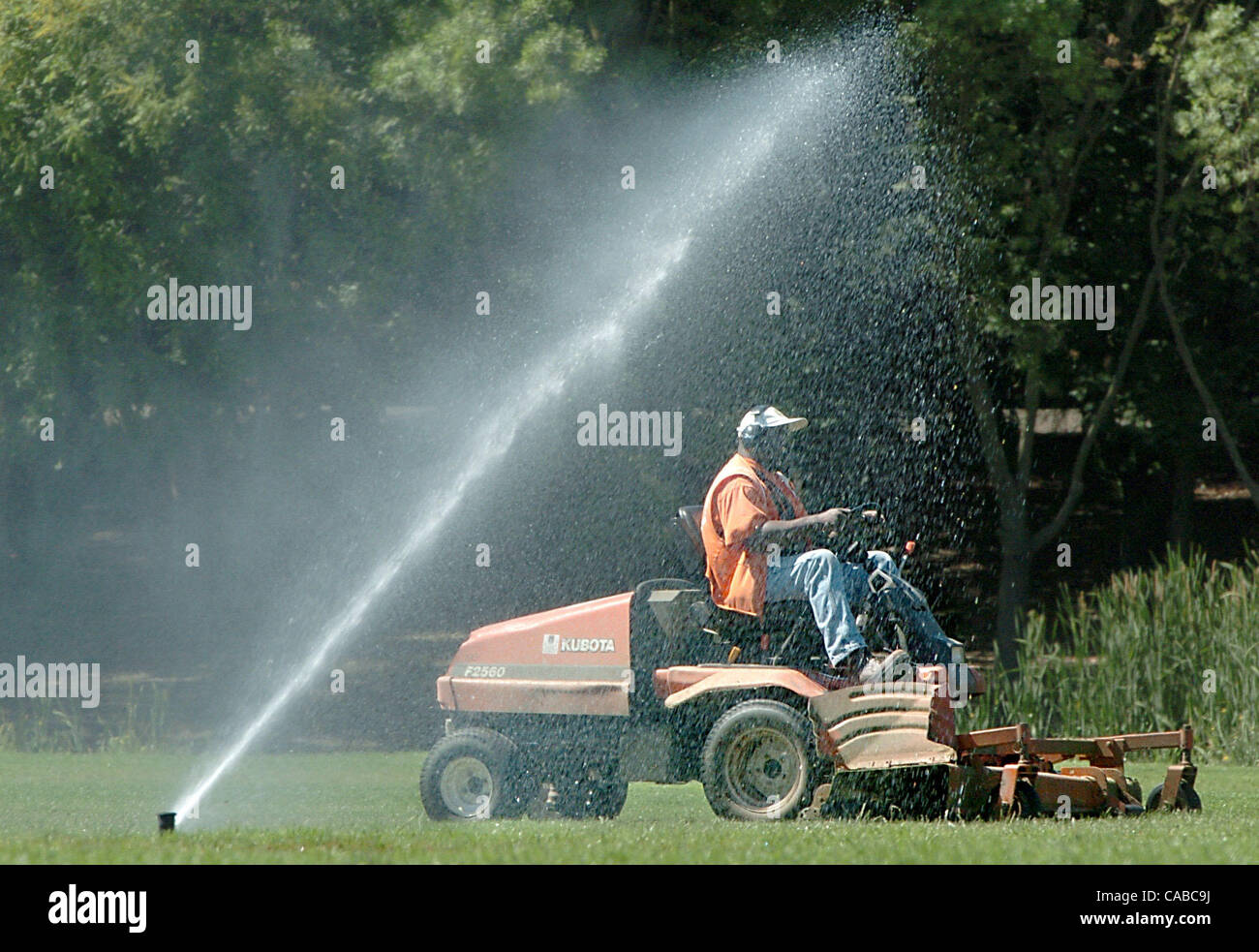 Paul Jet flirts with the water as he drives his lawnmower perilously close to a sprinkler Wednesday, June 2, 2004, as he mows Hillcrest park in Concord, Calif.  Jet, who works for the city of Concord, probably didn't mind a few sprinkles as the temperaturescontinued to climb    (Contra Costa Times/B Stock Photo