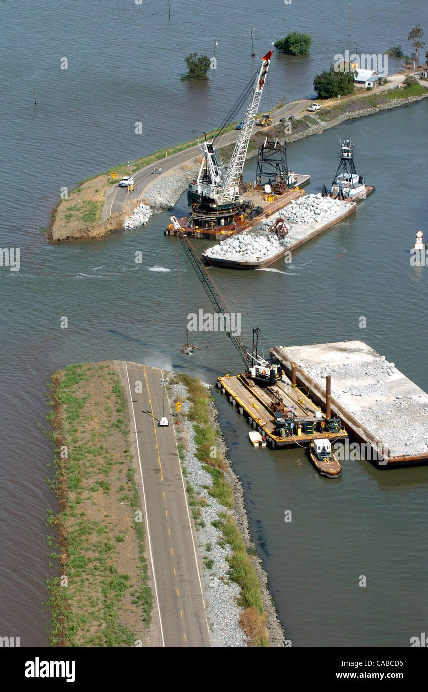 Workers using cranes and rock hauled in on barges try to repair the