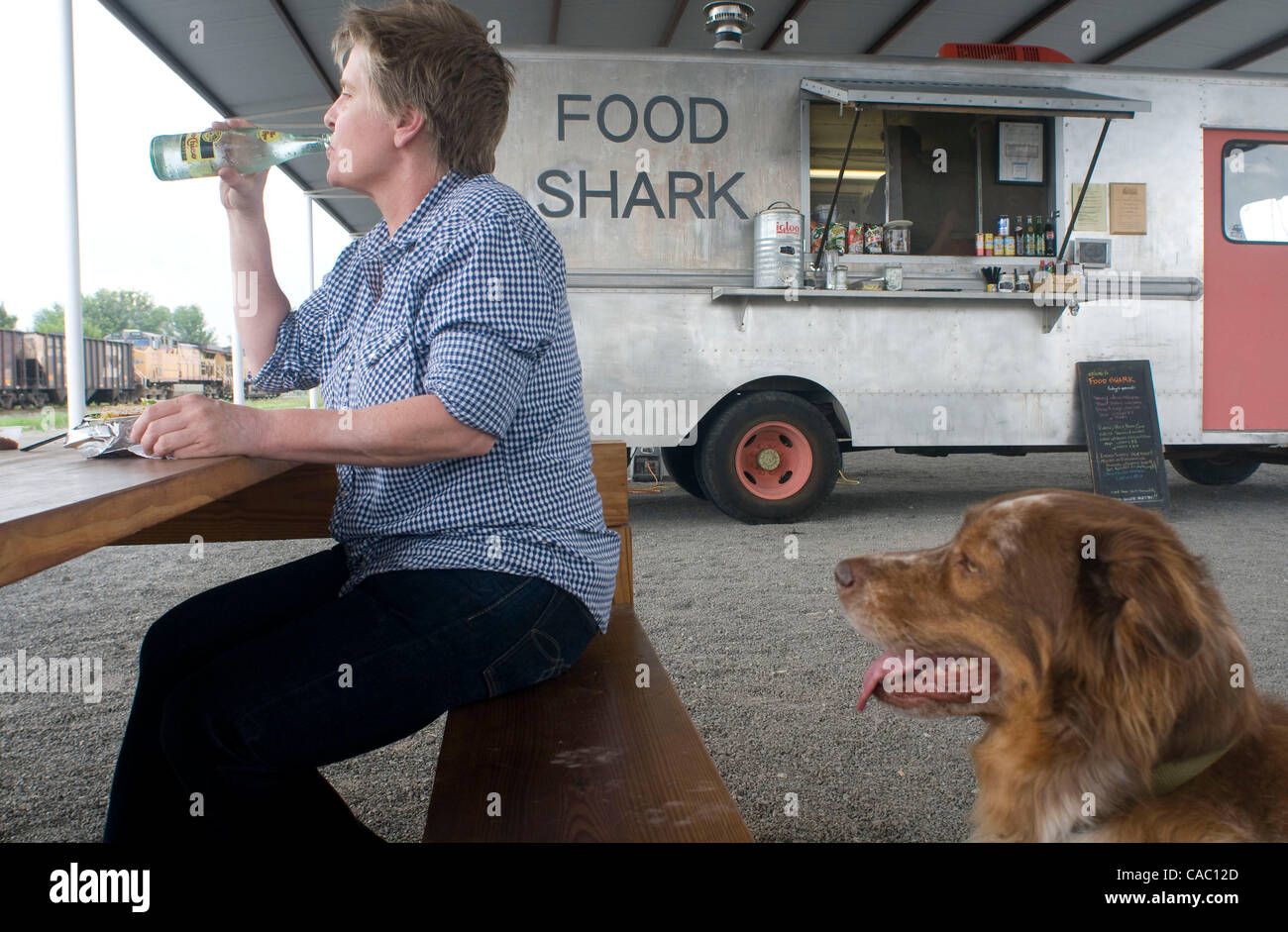 July 08, 2010 - Marfa, Texas, USA - July 8, 2010. LIZ LAMBERT has her lunch under the watchfull eyes of her dog Moses at The Food Shark food truck in Marfa, Texas  which is equipped with a kitchen and serves up a mix of Tex-Mex and vegetarian dishes emphasising natural ingredients and great taste. ( Stock Photo